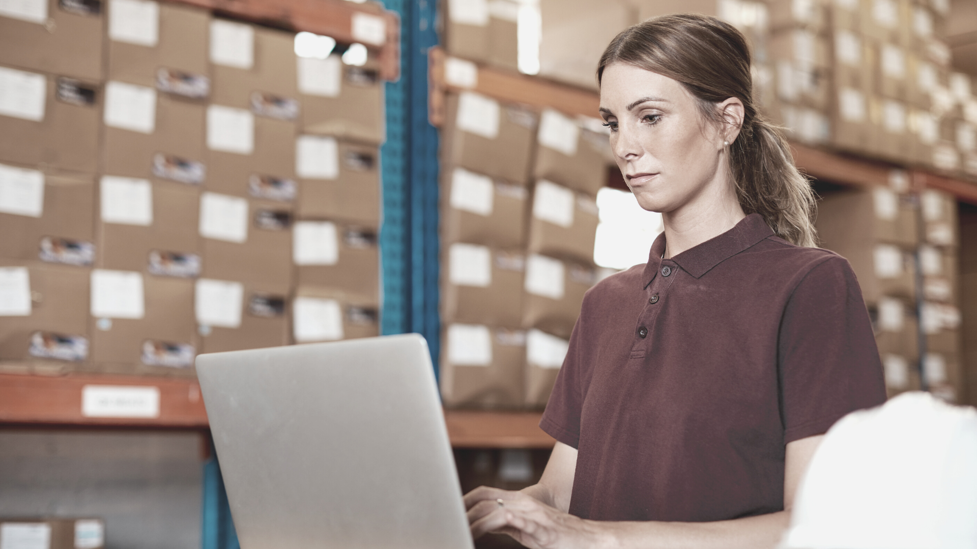 woman typing on laptop surrounded by boxes on shelves